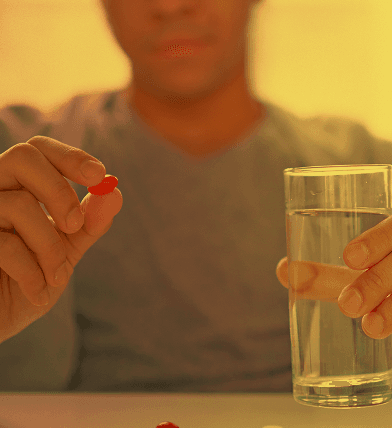 Man taking one AllNite capsule with a glass of water